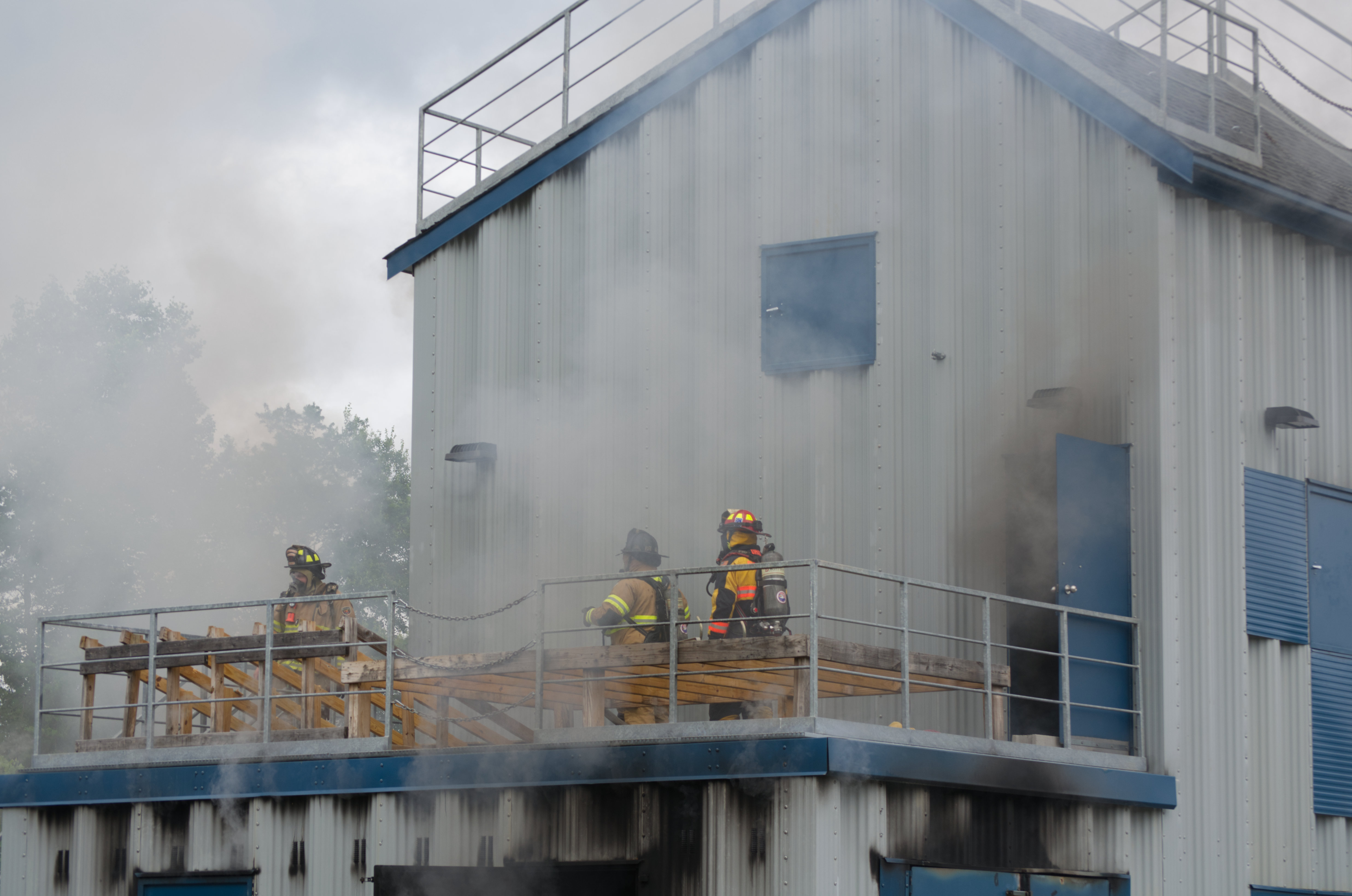 Training facility surrounded with smoke with 3 fire fighters working