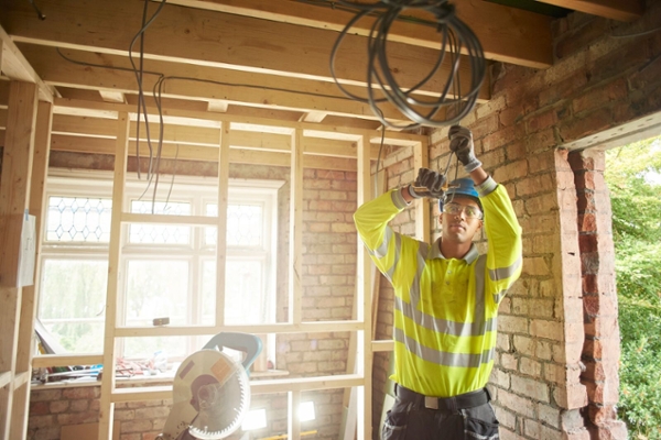 Electrician running wiring in an open ceiling